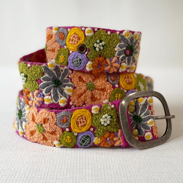 Photo of colorful hand-embroidered floral wool belt by Jenny Krauss, made in Peru with lead-free metal buckle. Versatile design with five sets of 2" spaced holes for hip or waist wear, featuring slight stretch for comfort.