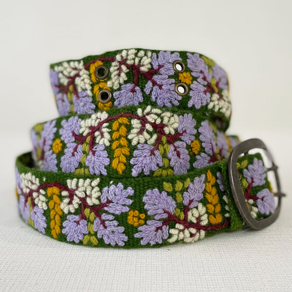 Photo of colorful hand-embroidered floral wool belt by Jenny Krauss, made in Peru with lead-free metal buckle. Versatile design with five sets of 2" spaced holes for hip or waist wear, featuring slight stretch for comfort.