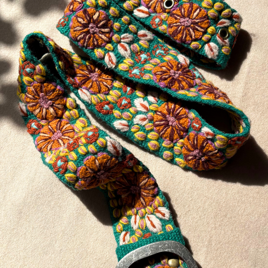 Photo of colorful hand-embroidered floral wool belt by Jenny Krauss, made in Peru with lead-free metal buckle. Versatile design with five sets of 2" spaced holes for hip or waist wear, featuring slight stretch for comfort.