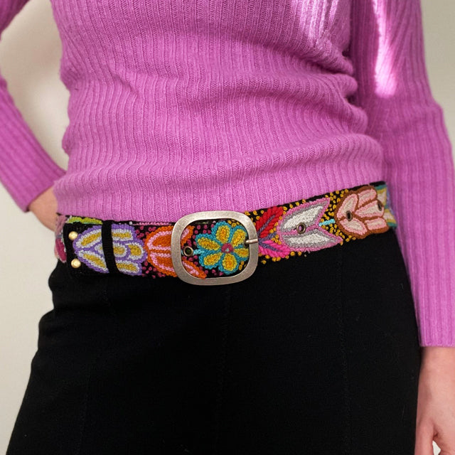 
Photo of colorful hand-embroidered floral wool belt by Jenny Krauss, made in Peru with lead-free metal buckle. Versatile design with five sets of 2" spaced holes for hip or waist wear, featuring slight stretch for comfort.
