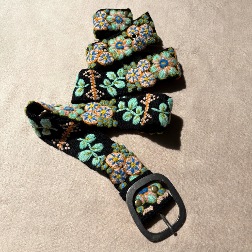 Photo of colorful hand-embroidered floral wool belt by Jenny Krauss, made in Peru with lead-free metal buckle. Versatile design with five sets of 2" spaced holes for hip or waist wear, featuring slight stretch for comfort.