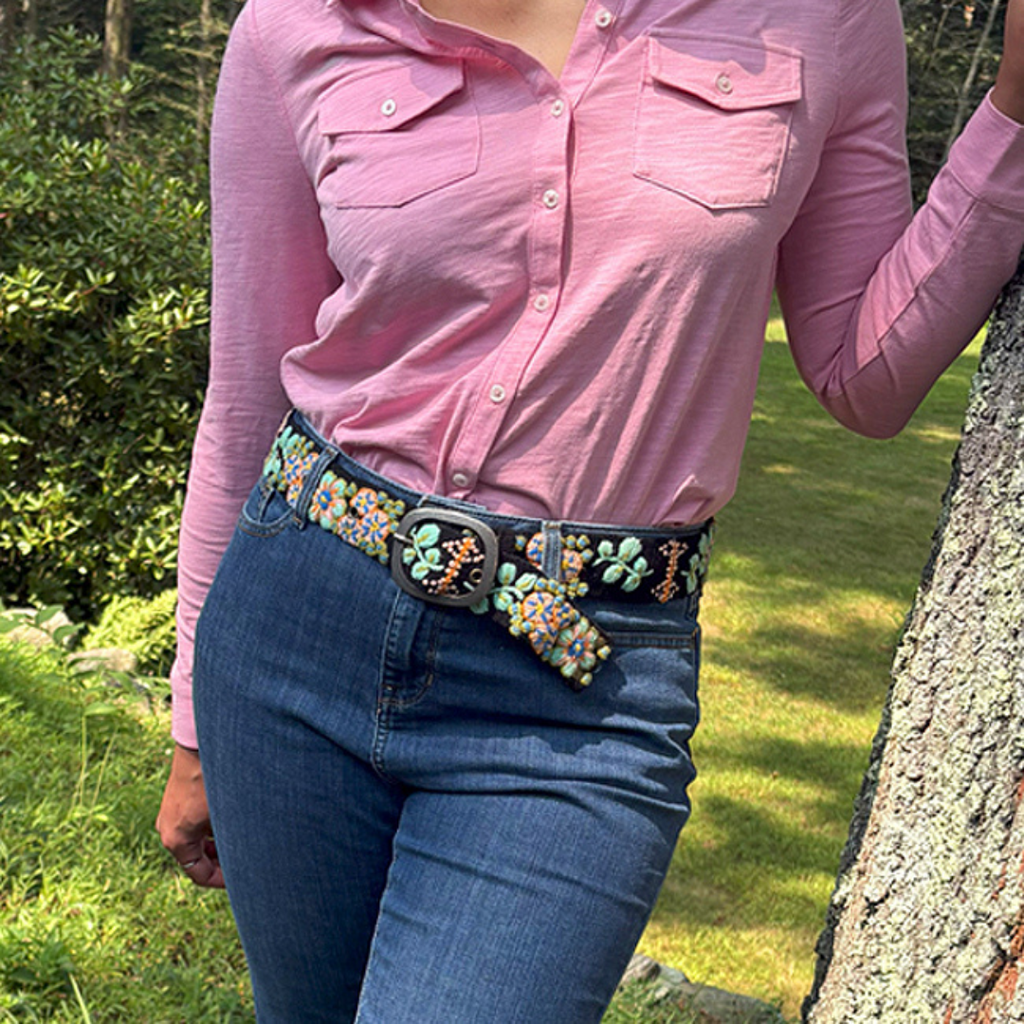Photo of woman wearing colorful hand-embroidered floral wool belt by Jenny Krauss, made in Peru with lead-free metal buckle. Versatile design with five sets of 2" spaced holes for hip or waist wear, featuring slight stretch for comfort.