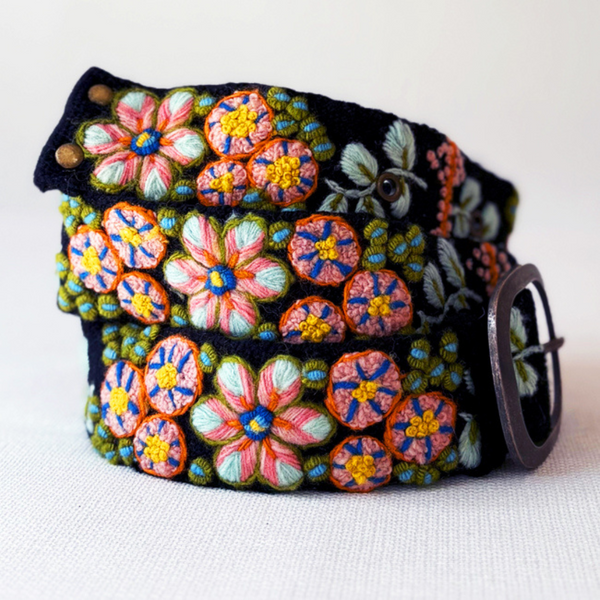 Photo of colorful hand-embroidered floral wool belt by Jenny Krauss, made in Peru with lead-free metal buckle. Versatile design with five sets of 2" spaced holes for hip or waist wear, featuring slight stretch for comfort.