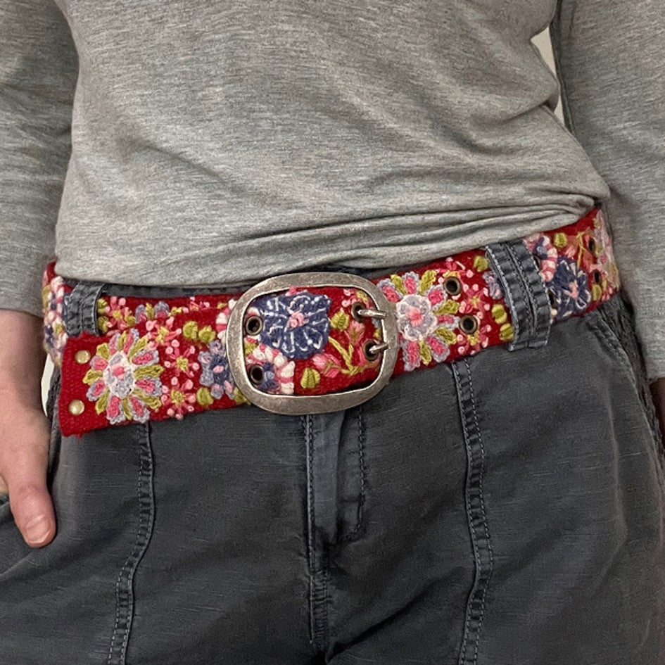 Photo of colorful hand-embroidered floral wool belt by Jenny Krauss, made in Peru with lead-free metal buckle. Versatile design with five sets of 2" spaced holes for hip or waist wear, featuring slight stretch for comfort.