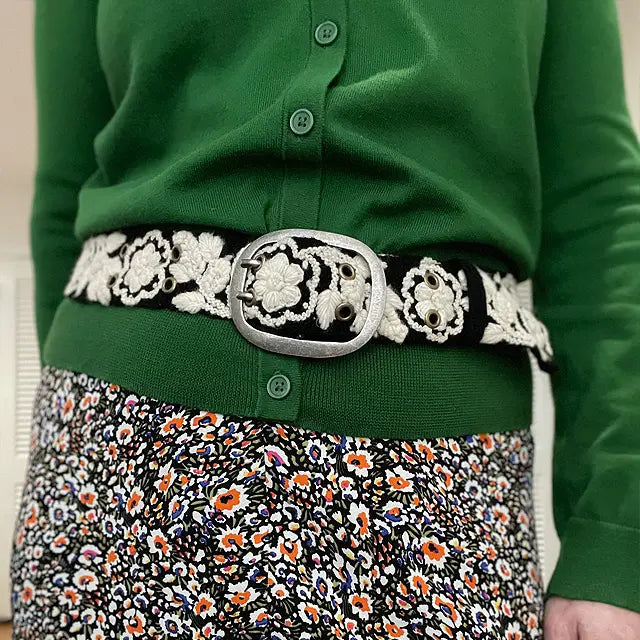 Photo of monochromatic  hand-embroidered floral wool belt by Jenny Krauss, made in Peru with lead-free metal buckle. Versatile design with five sets of 2" spaced holes for hip or waist wear, featuring slight stretch for comfort.