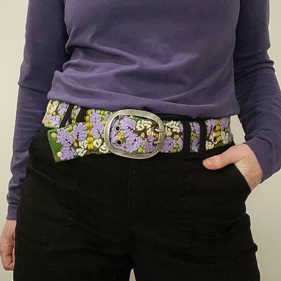 Photo of colorful hand-embroidered floral wool belt by Jenny Krauss, made in Peru with lead-free metal buckle. Versatile design with five sets of 2" spaced holes for hip or waist wear, featuring slight stretch for comfort.