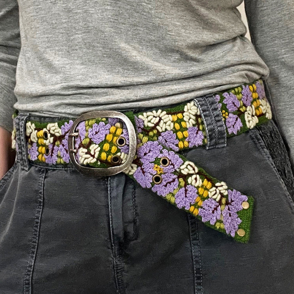 Photo of colorful hand-embroidered floral wool belt by Jenny Krauss, made in Peru with lead-free metal buckle. Versatile design with five sets of 2" spaced holes for hip or waist wear, featuring slight stretch for comfort.