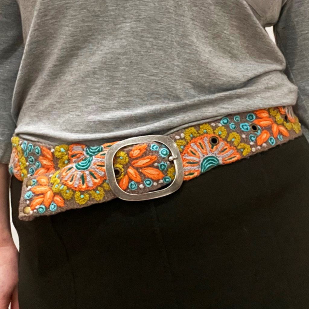 Photo of colorful hand-embroidered floral wool belt by Jenny Krauss, made in Peru with lead-free metal buckle. Versatile design with five sets of 2" spaced holes for hip or waist wear, featuring slight stretch for comfort.