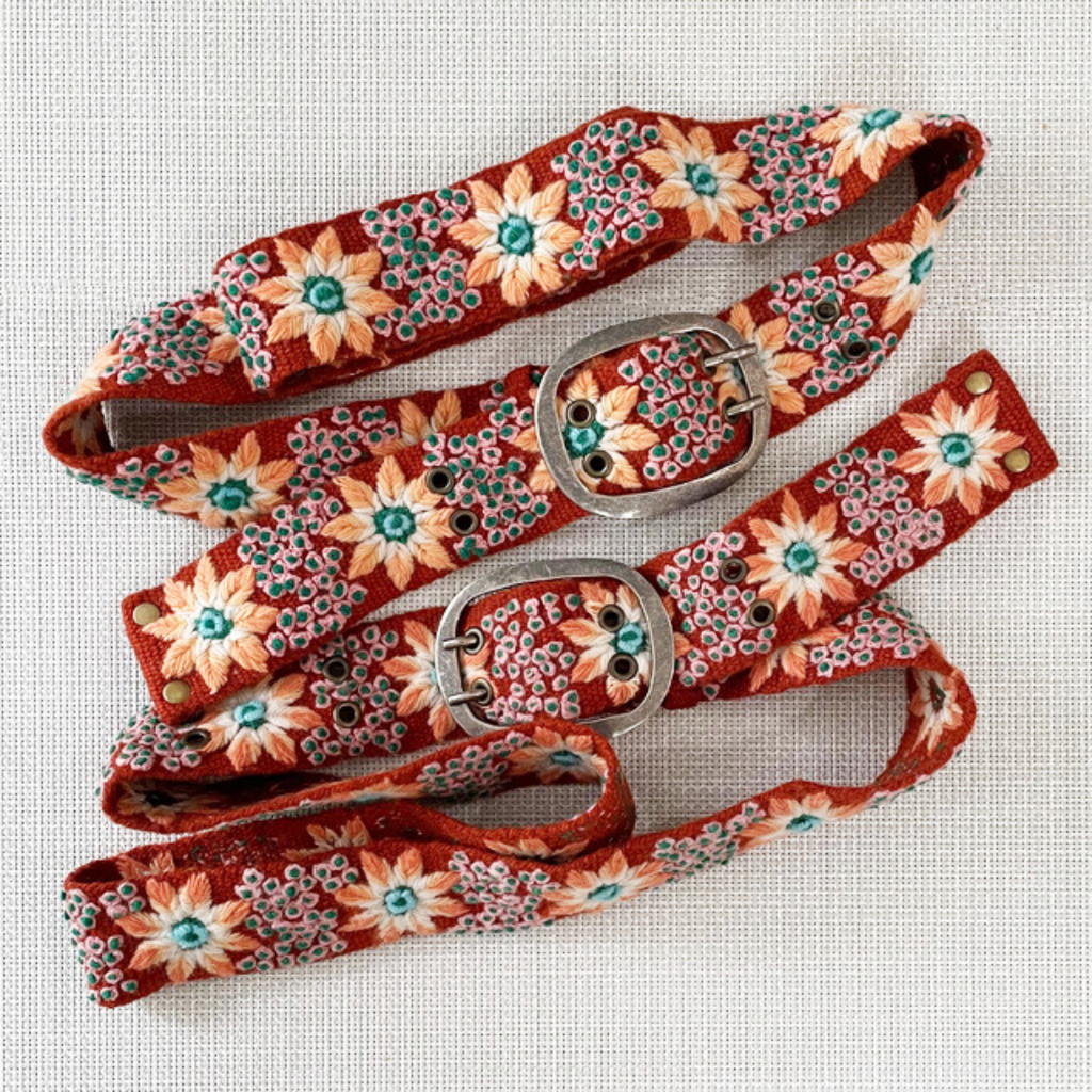 Photo of colorful hand-embroidered floral wool belt by Jenny Krauss, made in Peru with lead-free metal buckle. Versatile design with five sets of 2" spaced holes for hip or waist wear, featuring slight stretch for comfort.