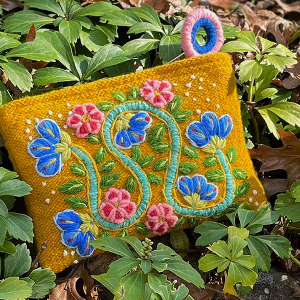 Photo of Jenny Krauss embroidered wool pouch, multi-functional travel accessory. Handcrafted with 100% wool, cotton lining, and sturdy metal zipper. Versatile for use as a wallet, clutch, or keepsake bag. Measures 5.5" L x 8" W. Designed in the U.S.A. and handmade in Peru by skilled artisans.