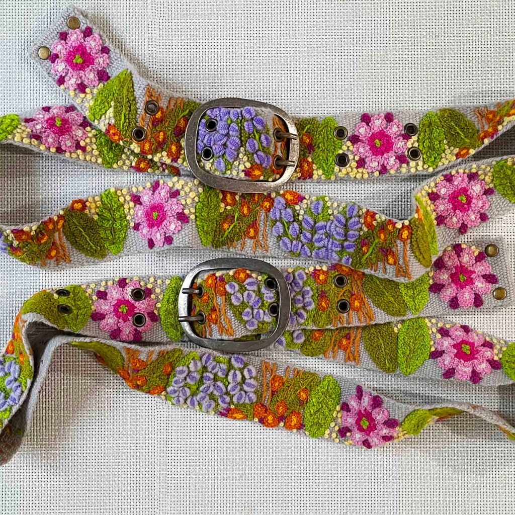 Photo of colorful hand-embroidered floral wool belt by Jenny Krauss, made in Peru with lead-free metal buckle. Versatile design with five sets of 2" spaced holes for hip or waist wear, featuring slight stretch for comfort.