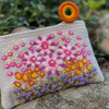 Photo of Jenny Krauss embroidered wool pouch, multi-functional travel accessory. Handcrafted with 100% wool, cotton lining, and sturdy metal zipper. Versatile for use as a wallet, clutch, or keepsake bag. Measures 5.5" L x 8" W. Designed in the U.S.A. and handmade in Peru by skilled artisans.