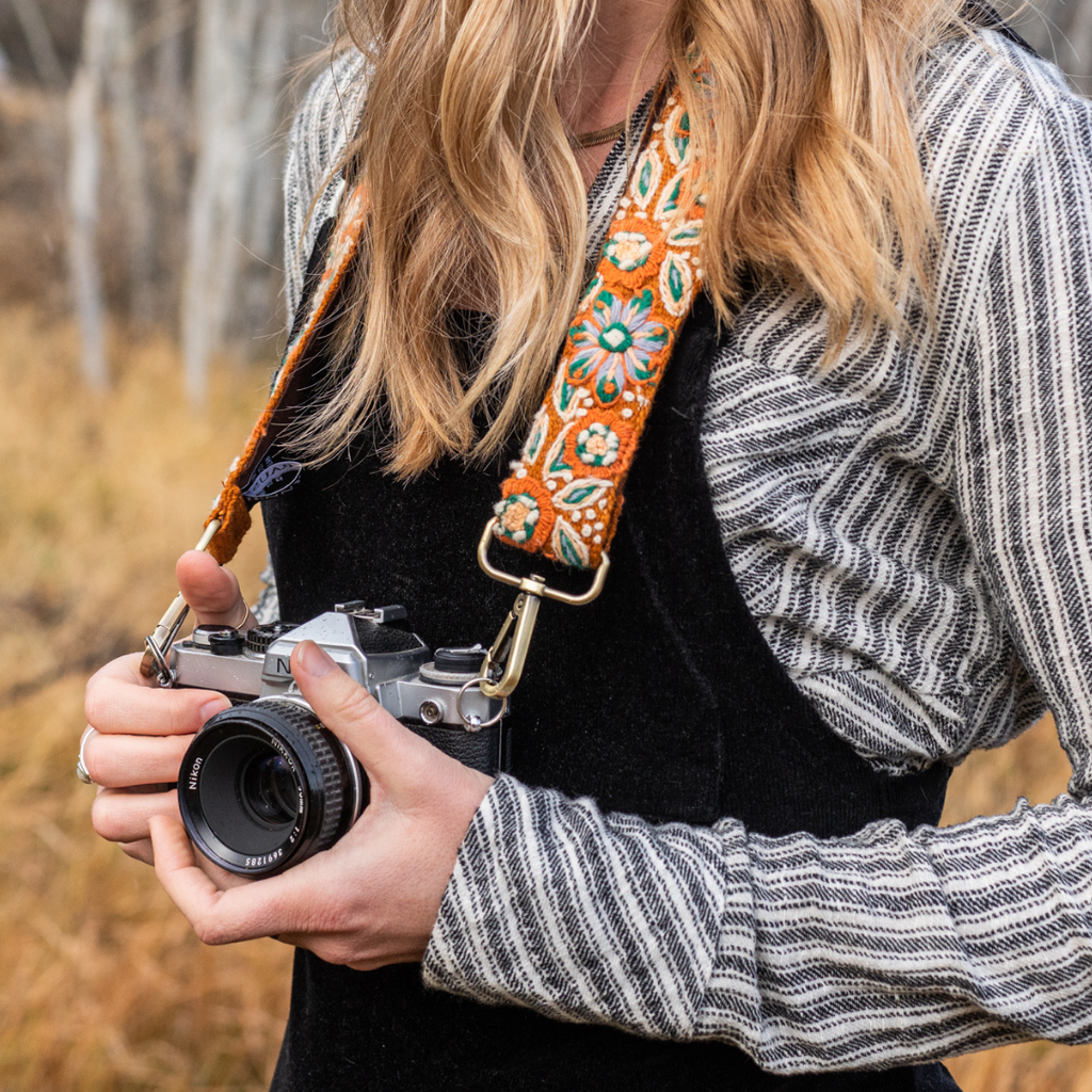 Photo of Jenny Krauss hand-embroidered wool strap from Peru. Multi-functional design serves as a bag or camera strap. Vibrant floral pattern, lead-free metal hardware, and adjustable length for versatile use. Elevate your style with this artisanal accessory.