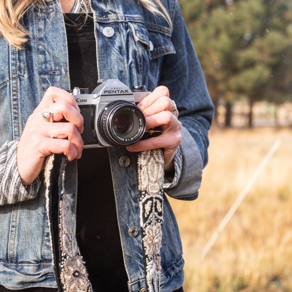 Photo of Jenny Krauss hand-embroidered wool strap from Peru. Multi-functional design serves as a camera or bag strap. Monochromatic floral pattern, lead-free metal hardware, and adjustable length for versatile use. Elevate your style with this artisanal accessory.