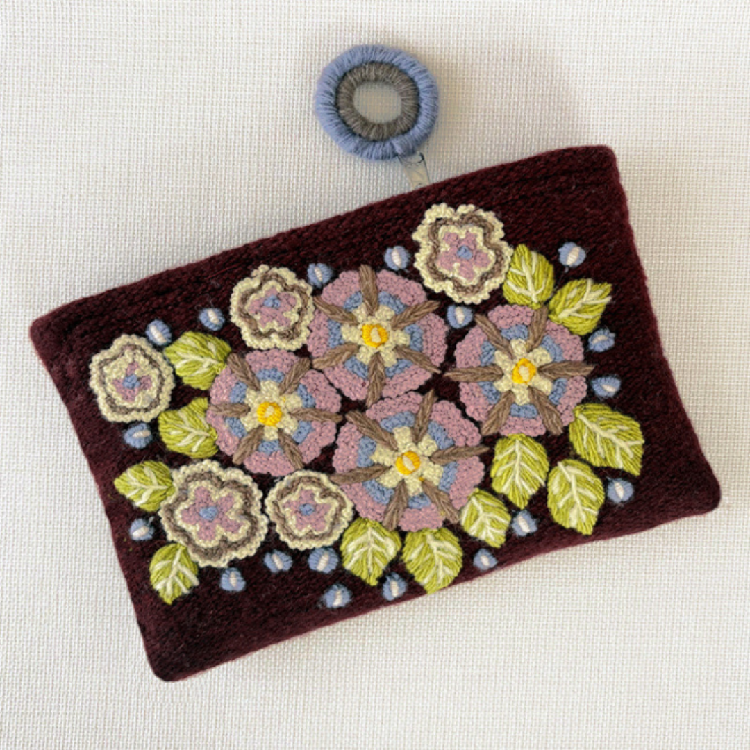 Photo of Jenny Krauss embroidered wool pouch, multi-functional travel accessory. Handcrafted with 100% wool, cotton lining, and sturdy metal zipper. Versatile for use as a wallet, clutch, or keepsake bag. Measures 5.5" L x 8" W. Designed in the U.S.A. and handmade in Peru by skilled artisans.