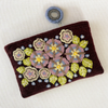 Photo of Jenny Krauss embroidered wool pouch, multi-functional travel accessory. Handcrafted with 100% wool, cotton lining, and sturdy metal zipper. Versatile for use as a wallet, clutch, or keepsake bag. Measures 5.5" L x 8" W. Designed in the U.S.A. and handmade in Peru by skilled artisans.