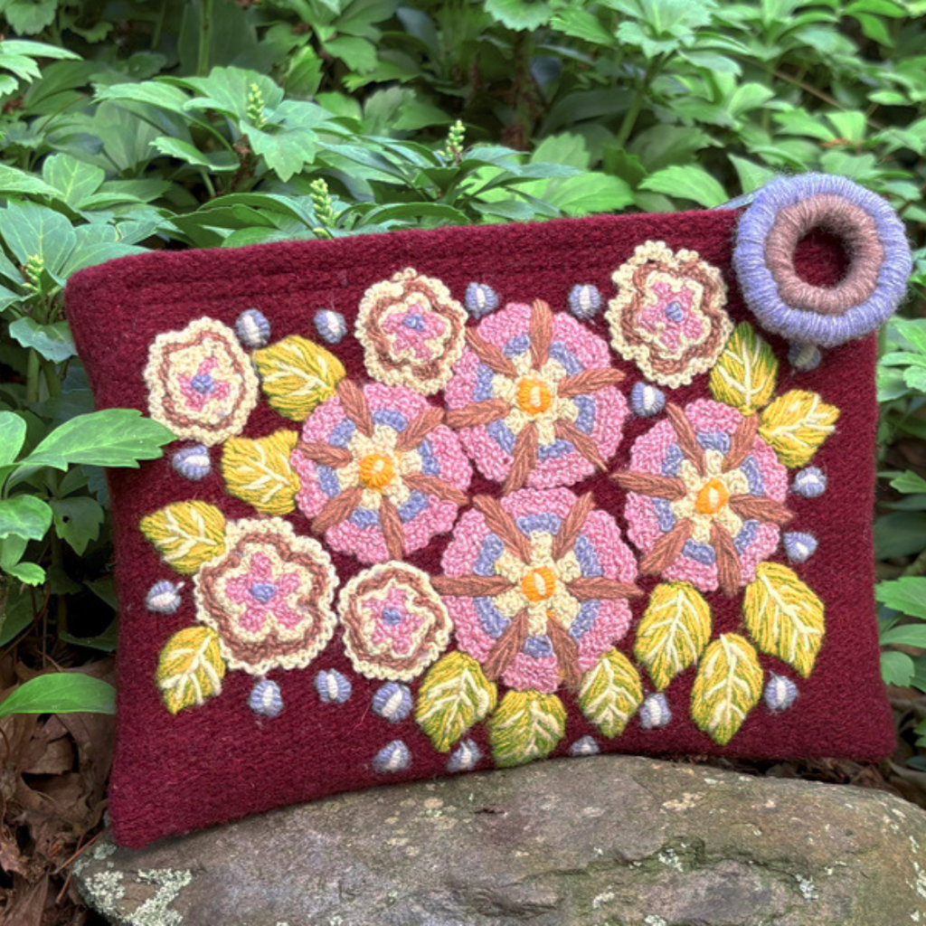 Photo of Jenny Krauss embroidered wool pouch, multi-functional travel accessory. Handcrafted with 100% wool, cotton lining, and sturdy metal zipper. Versatile for use as a wallet, clutch, or keepsake bag. Measures 5.5" L x 8" W. Designed in the U.S.A. and handmade in Peru by skilled artisans.