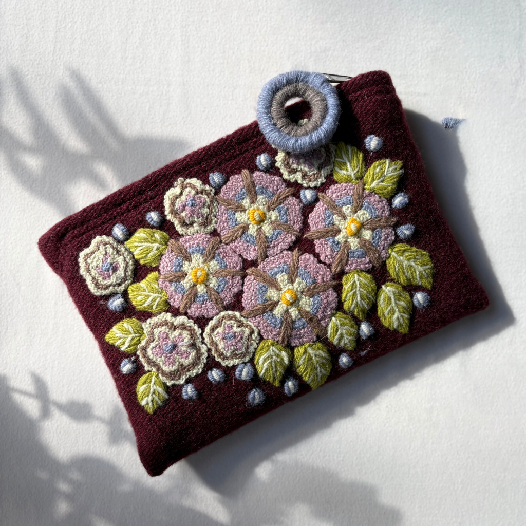 Handcrafted pouch with floral embroidery on a white background