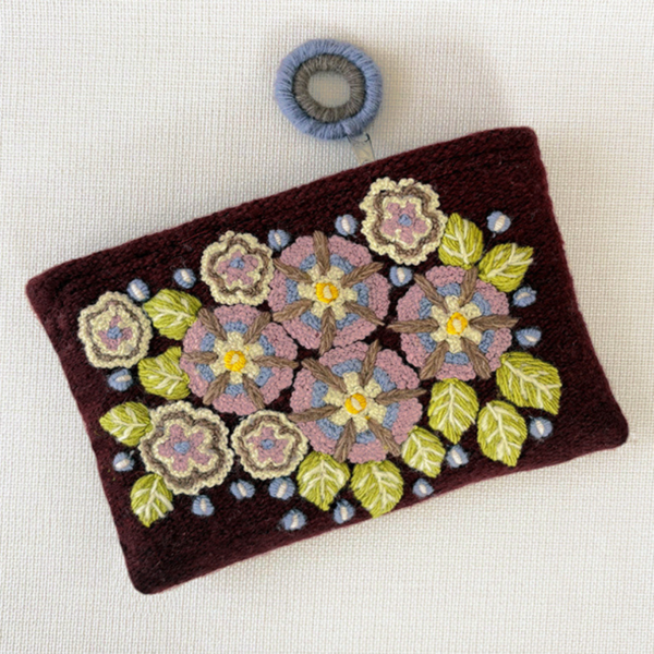 Photo of Jenny Krauss embroidered wool pouch, multi-functional travel accessory. Handcrafted with 100% wool, cotton lining, and sturdy metal zipper. Versatile for use as a wallet, clutch, or keepsake bag. Measures 5.5" L x 8" W. Designed in the U.S.A. and handmade in Peru by skilled artisans.