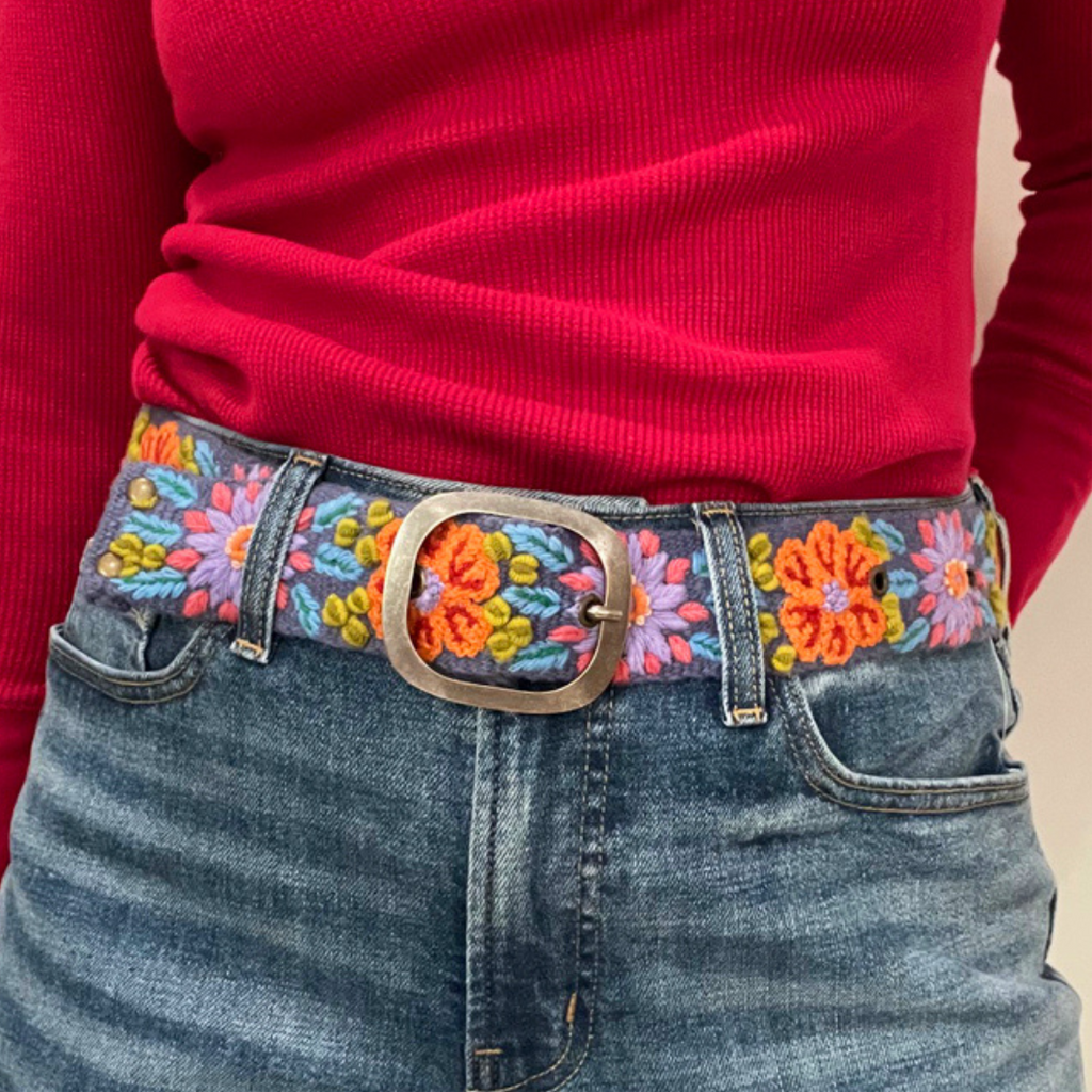 Photo of colorful hand-embroidered floral wool belt by Jenny Krauss, made in Peru with lead-free metal buckle. Versatile design with five sets of 2" spaced holes for hip or waist wear, featuring slight stretch for comfort.