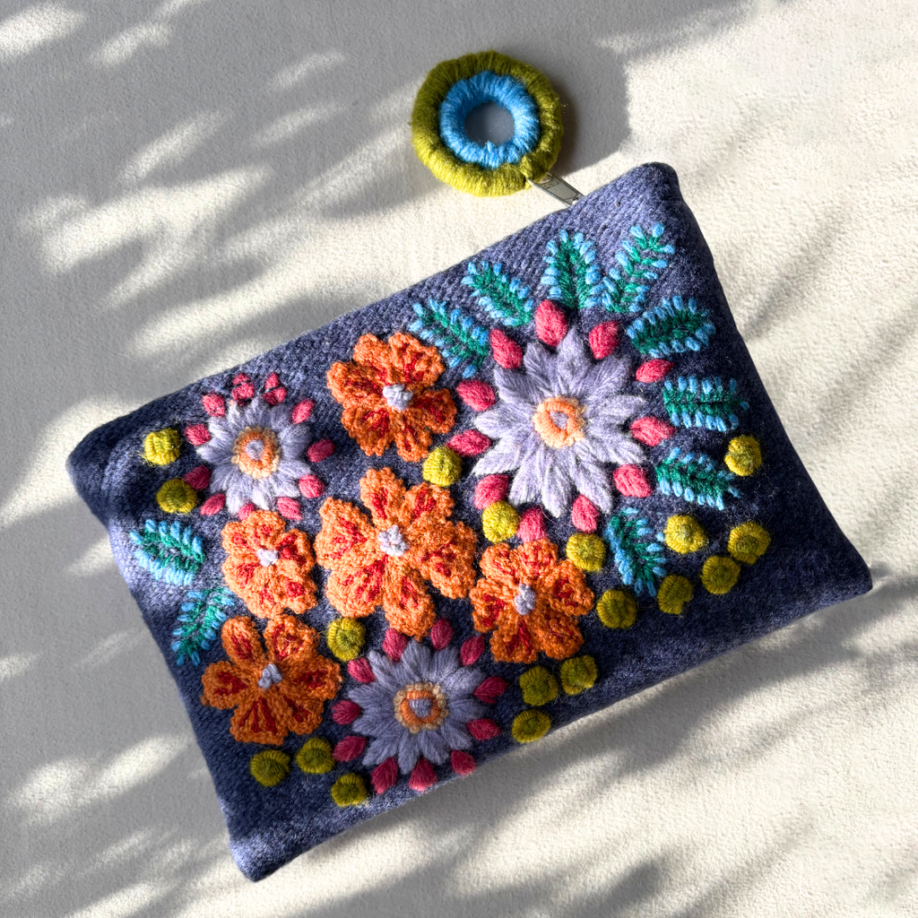 Colorful embroidered pouch with floral patterns on a light background