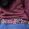 Photo of colorful hand-embroidered floral wool belt by Jenny Krauss, made in Peru with lead-free metal buckle. Versatile design with five sets of 2" spaced holes for hip or waist wear, featuring slight stretch for comfort.